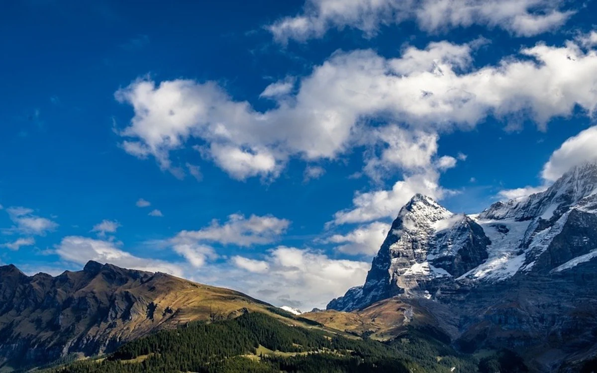 Snow-covered peaks standing above a layer of cloud with a wing in the foreground